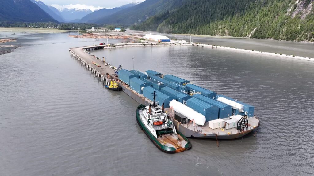 Foss Maritime cargo ship with containers on a river, surrounded by mountains.